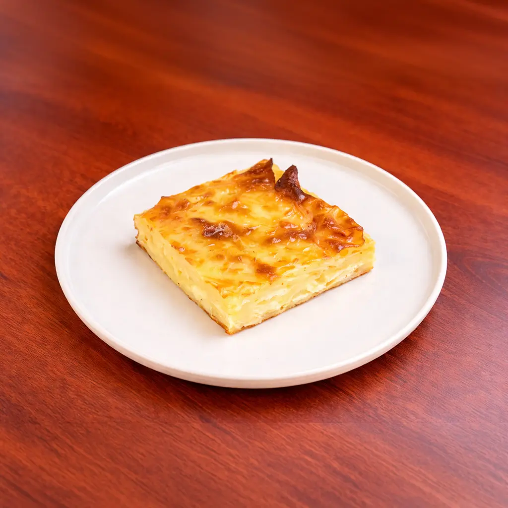 Baked layered cheese börek square with golden bubbly top crust served on a white ceramic plate at Cafe Galata Guelph