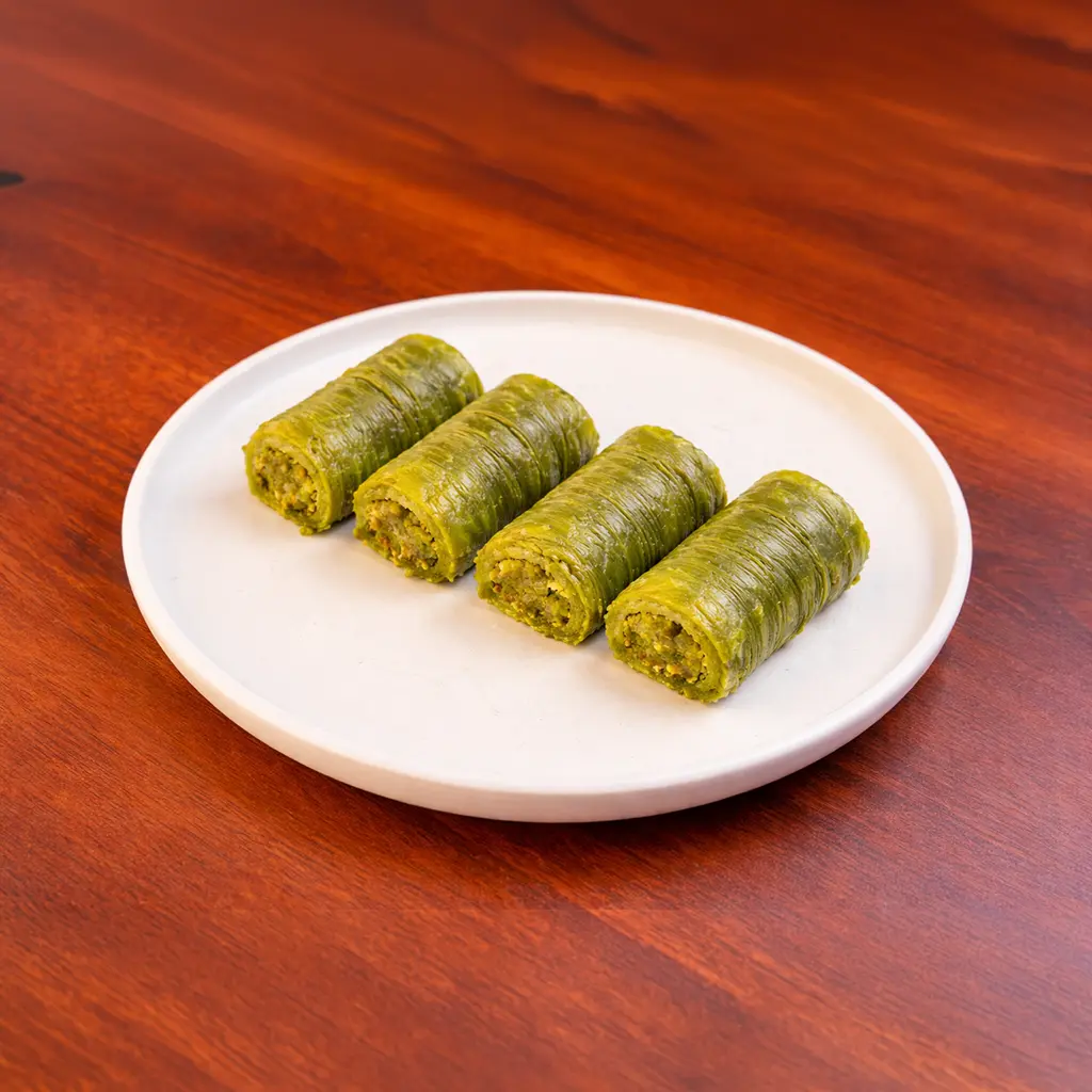 Four pistachio cranberry Turkish delight crescent rolls coated in crushed green pistachio on a round wooden serving board at Cafe Galata Guelph