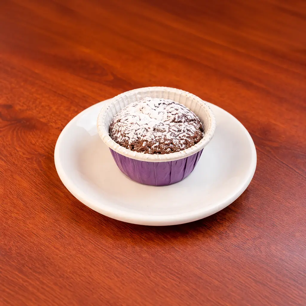 Individual chocolate lava cake in a purple baking cup dusted with powdered sugar served on a white plate at Cafe Galata Guelph