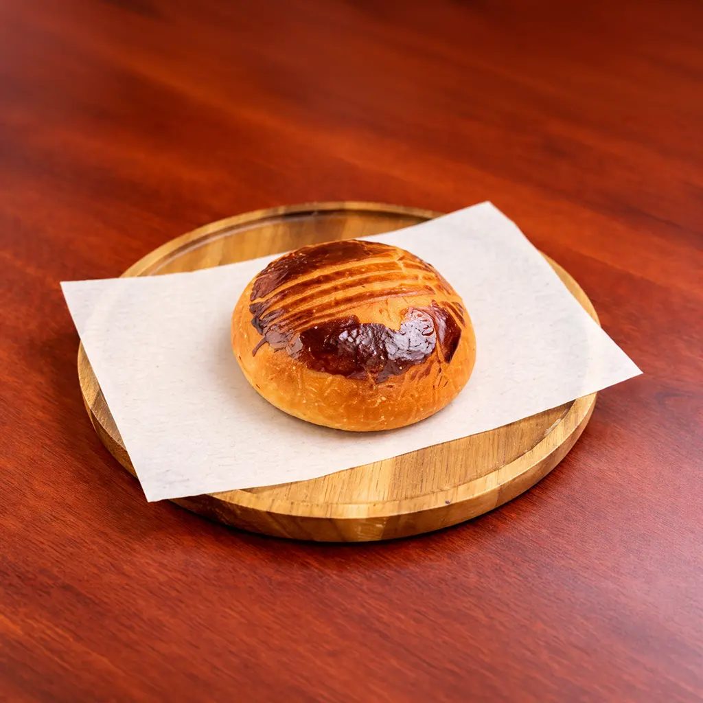 Plain savory Turkish poğaça bun with a glossy golden crust served on parchment paper on a wooden board at Cafe Galata Guelph