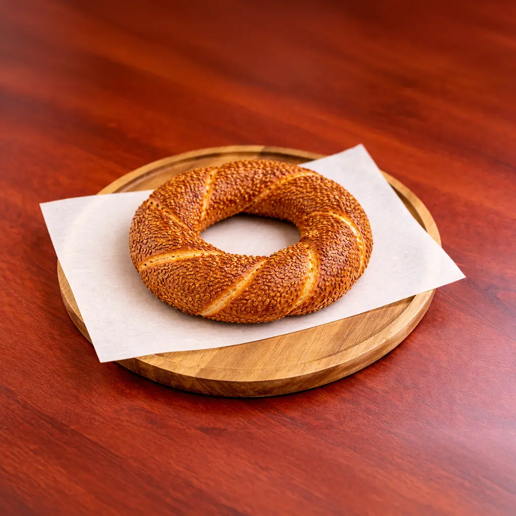 Traditional Turkish simit sesame seed bagel ring served on parchment paper on a round wooden board at Cafe Galata Guelph