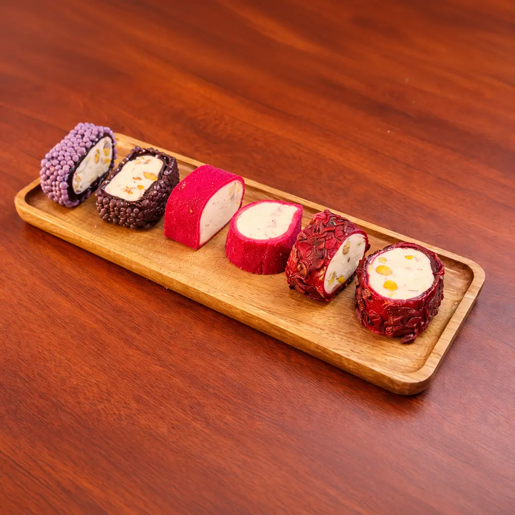Turkish delight lokum pieces in purple, dark chocolate and crimson coatings sliced to reveal creamy nut filling on a wooden board at Cafe Galata